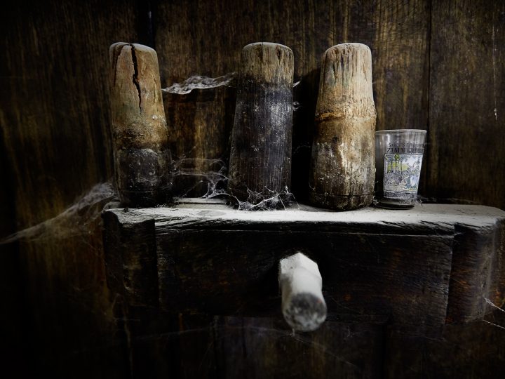 Alte Holzwerkzeuge und Glas in staubiger Ecke