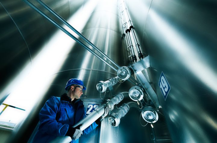 Arbeiter inspiziert Rohre in großer Metallanlage.