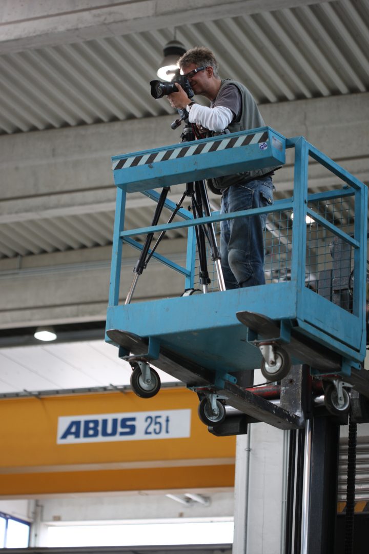 Fotograf auf Hebebühne im Industrierahmen fotografieren