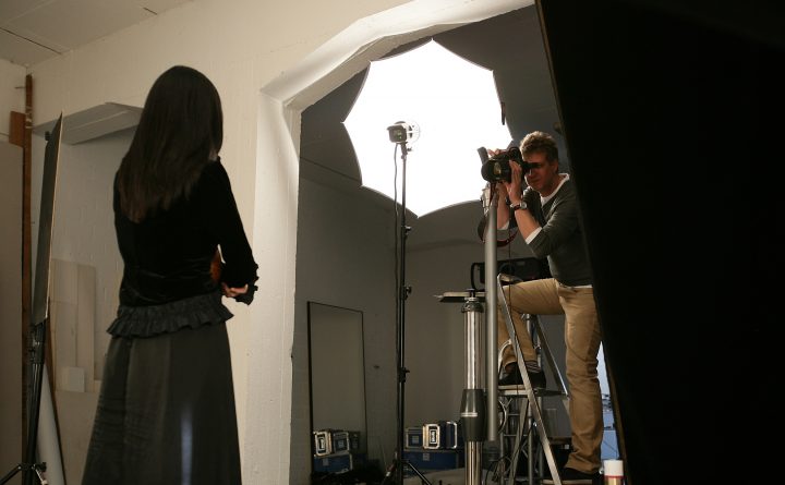 Fotograf fotografiert Model im Studio mit Beleuchtung