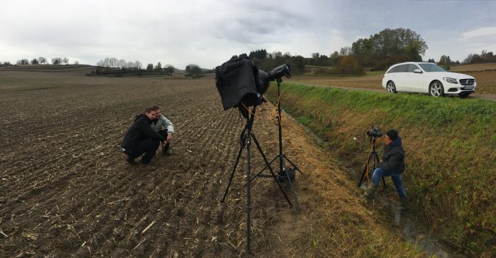 Fotograf im Feld mit Kamera und Auto