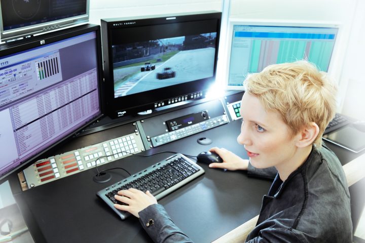 Frau arbeitet im Kontrollraum mit Computern