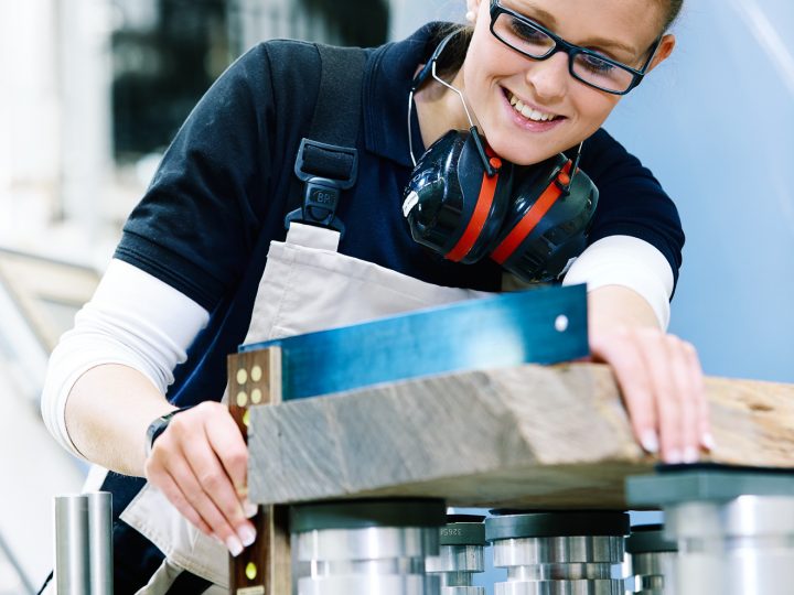 Frau arbeitet in Werkstatt mit Metallmaschine