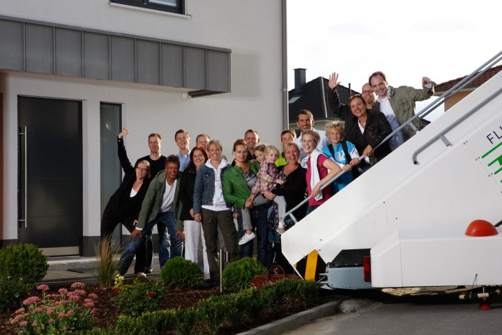 Gruppe von lachenden Menschen vor einem Haus