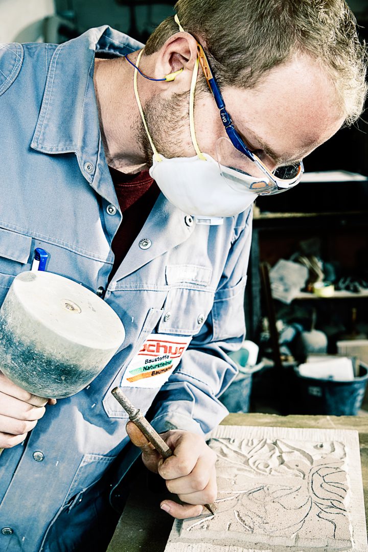Handwerker schnitzt Muster in Steinplatte