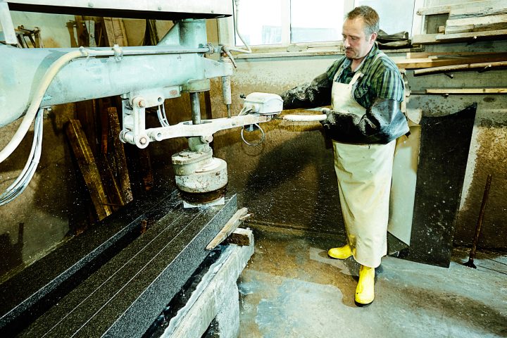 Mann arbeitet an einer Steinschneidemaschine in Werkstatt.