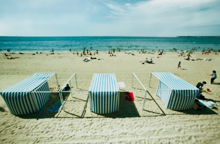 Menschen am Strand mit gestreiften Sonnenschirmen