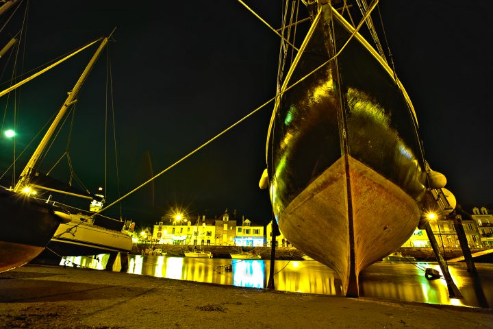 Nachthafen mit beleuchtetem Segelschiff und Gebäuden
