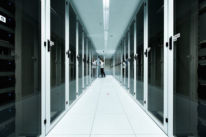 Person im Serverraum mit Servern und Glaswänden