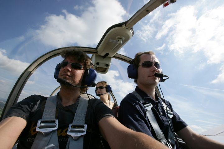 Piloten im Cockpit eines Flugzeugs, Himmel bewölkt.