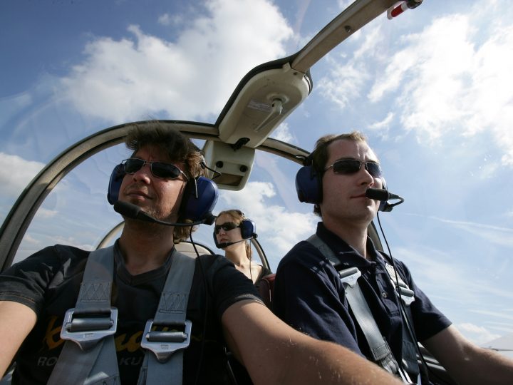 Piloten im Cockpit eines Flugzeugs, Himmel bewölkt.