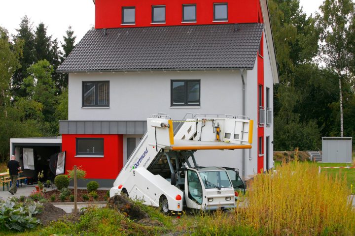 Rotes Haus mit Flughafenfahrzeug im Garten