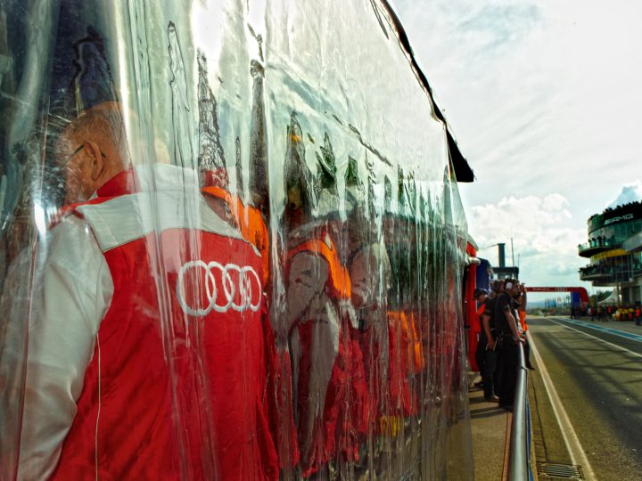 Team hinter transparenter Trennwand bei Rennstrecke