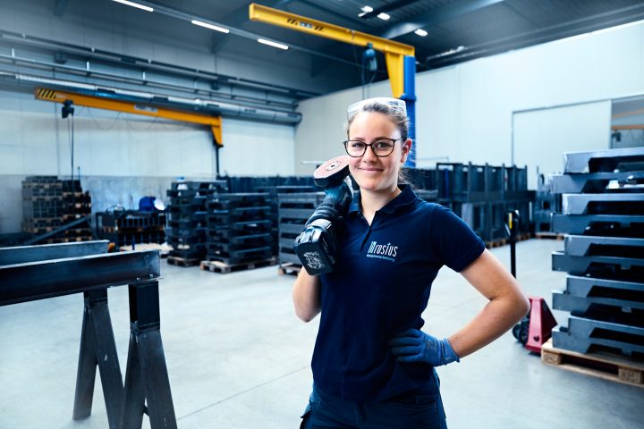 Frau mit Schleifmaschine in Werkhalle