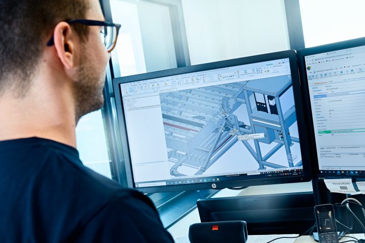 Ingenieur arbeitet mit CAD-Software an zwei Bildschirmen.