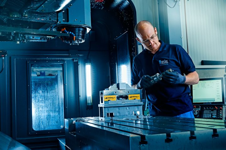 Mann bedient CNC-Maschine in Fertigungswerkstatt.