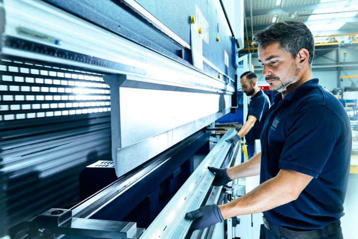 Mitarbeiter bedient industrielle Biegemaschine in Fabrikhalle.