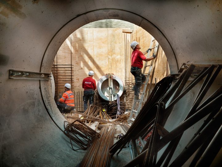 Arbeiter arbeiten im Rohrbau mit Leitern und Werkzeugen.