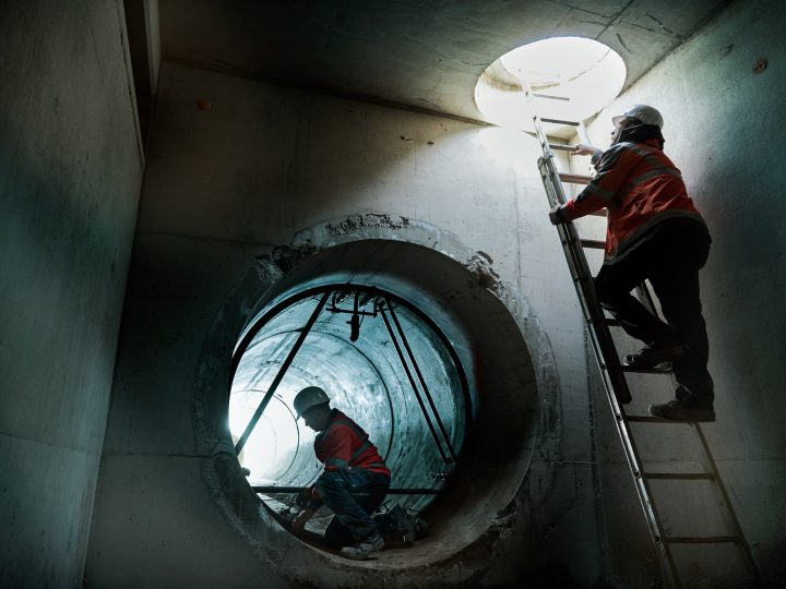 Arbeiter im Kanalrohr bei Bauarbeiten, mit Leiter.