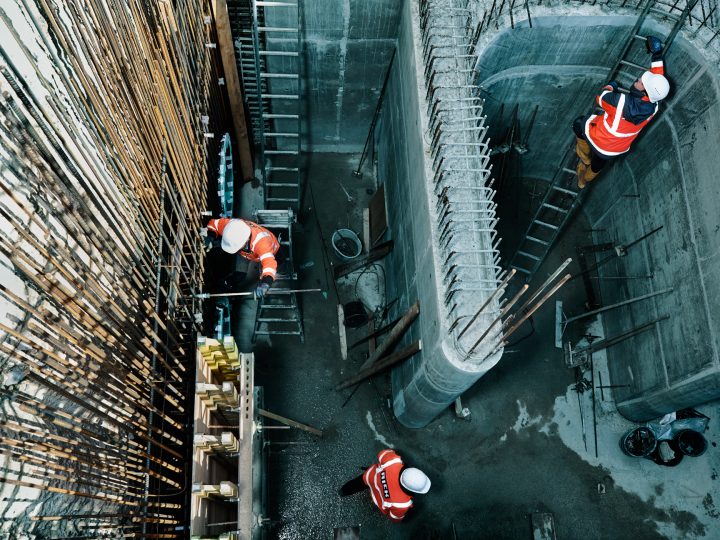 Bauarbeiter auf Baustelle in Sicherheitskleidung und Helmen.