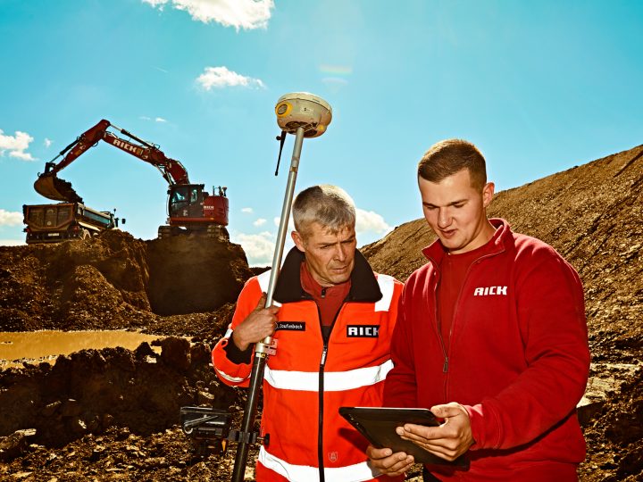 Bauarbeiter bei Erdarbeiten mit Bagger und Tablet