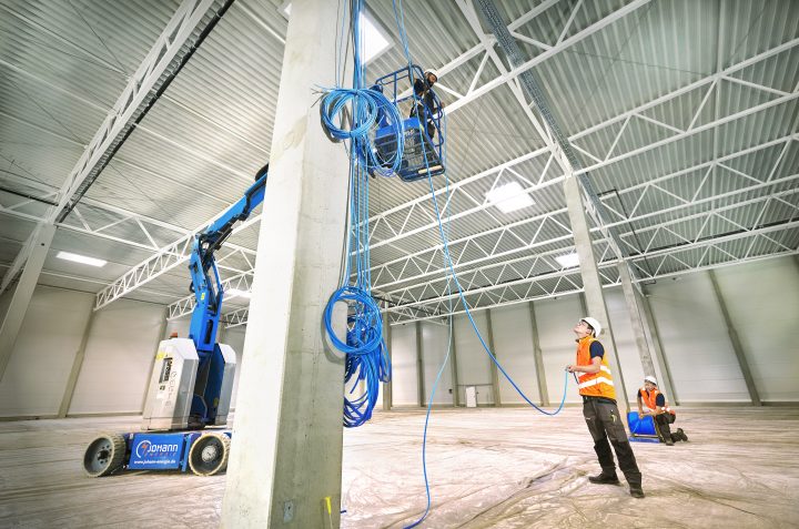Arbeiter installieren blaue Kabel im Industriebau.