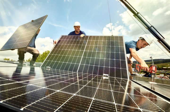 Arbeiter installieren Solaranlagen auf einem Dach.