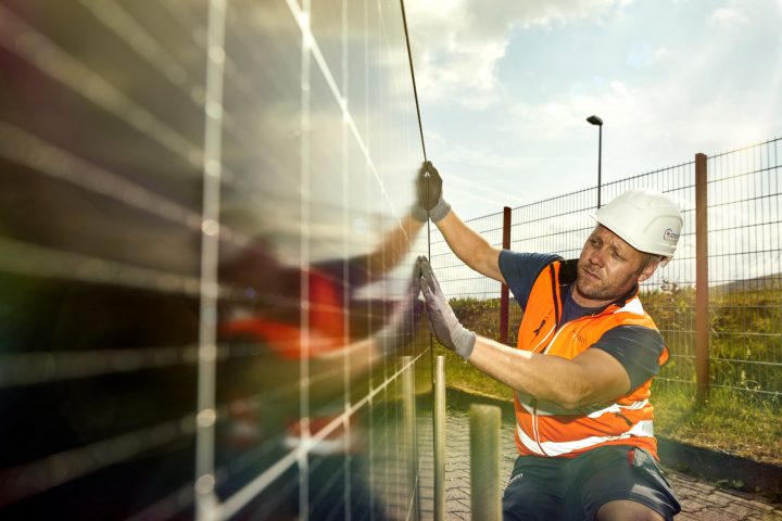 Arbeiter installiert Solarpanel auf einem Dach.